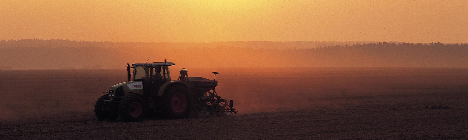 A tractor plowing a field at sunset