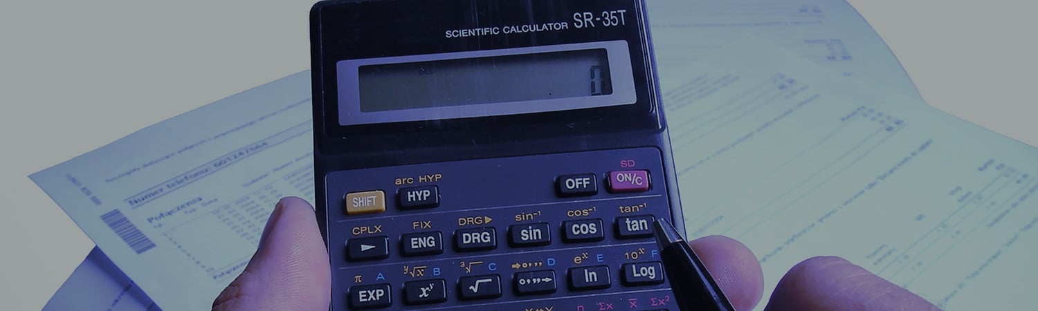 Close up shot of a man using a calculator with bills in the background.